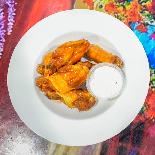 ELE PIZZA's buffalo wings, glistening with sauce, served with a side of ranch dressing.