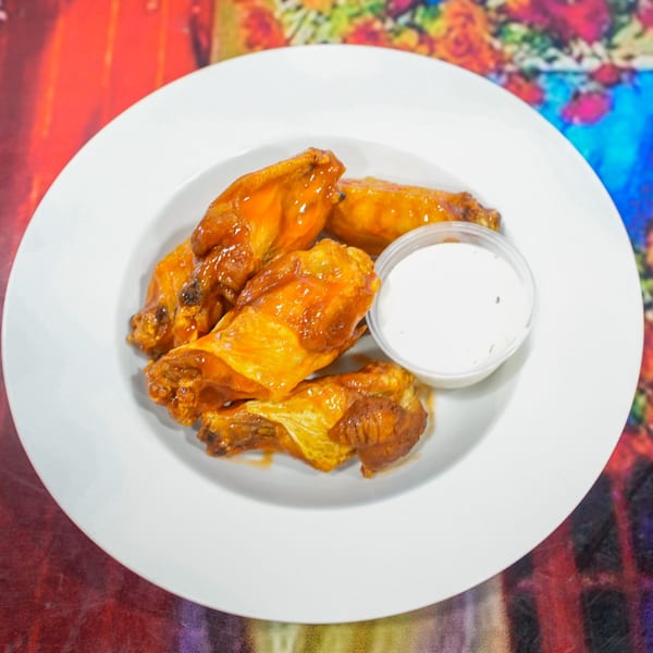 ELE PIZZA's buffalo wings, glistening with sauce, served with a side of creamy ranch dip.
