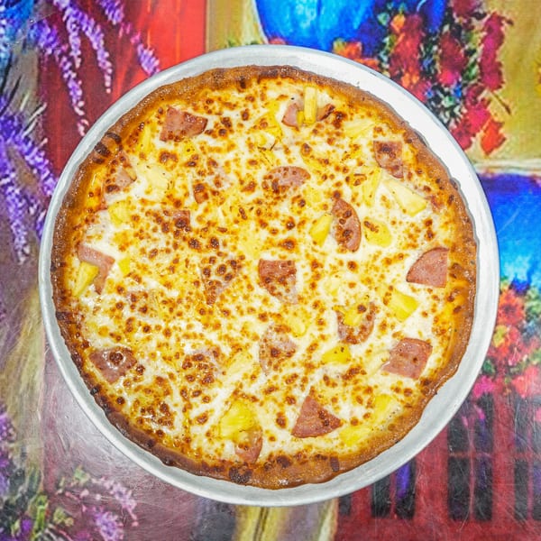 ELE PIZZA's Hawaiian pizza with ham and pineapple on a colorful floral background.