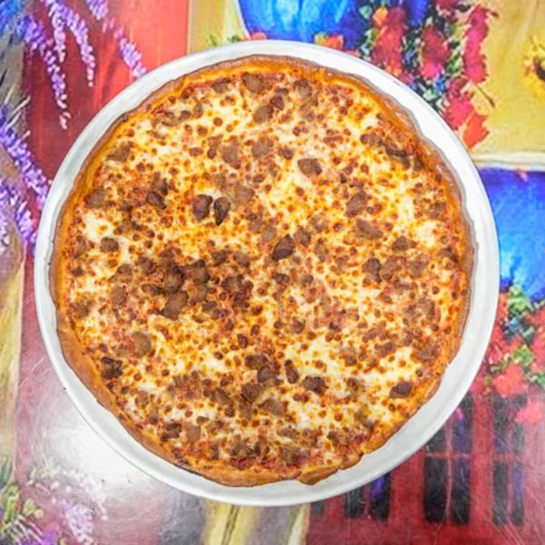 ELE PIZZA's sausage pizza, topped with melted cheese and savory sausage crumbles, on a colorful tablecloth.